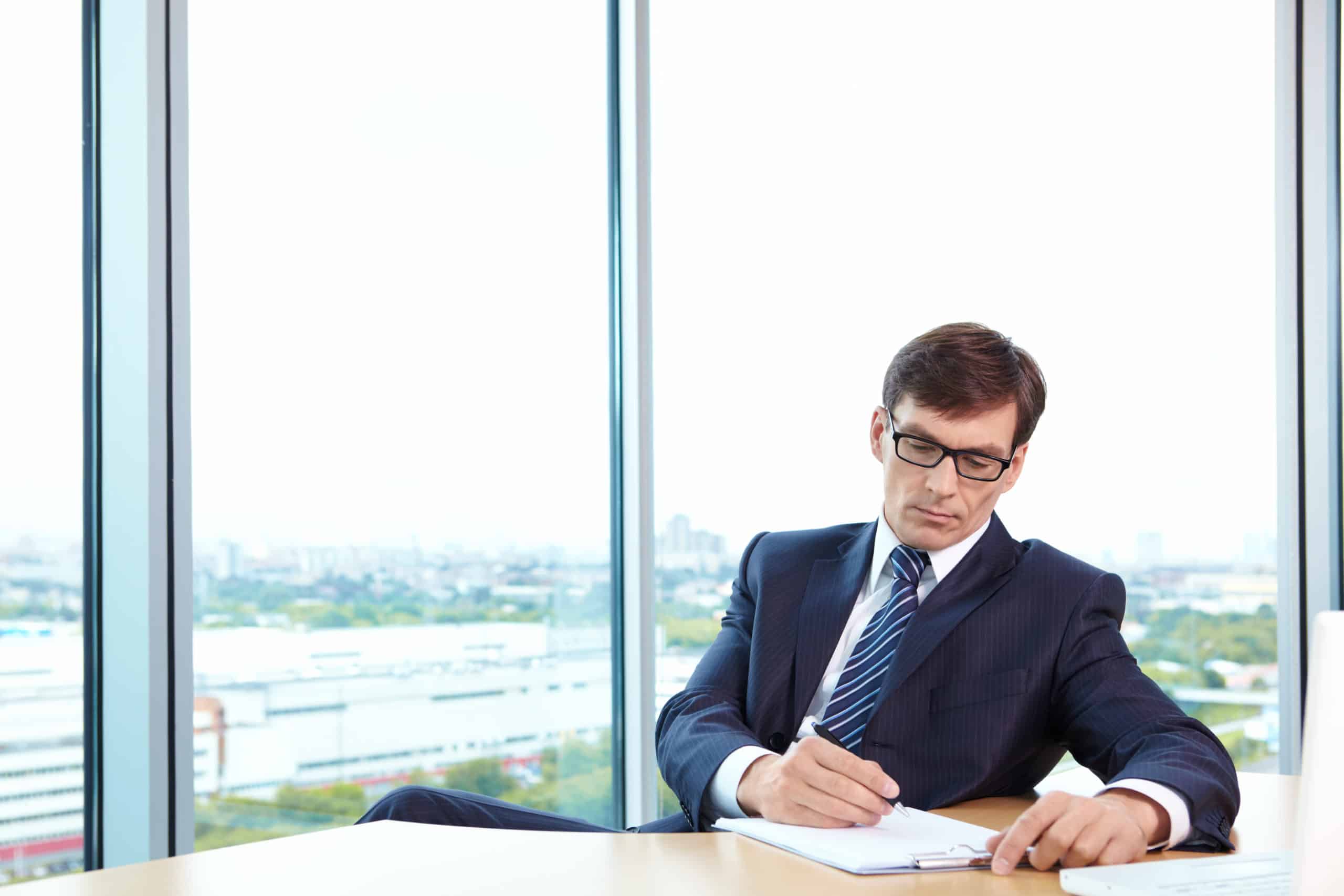 A man in business suit signs documents in the office
